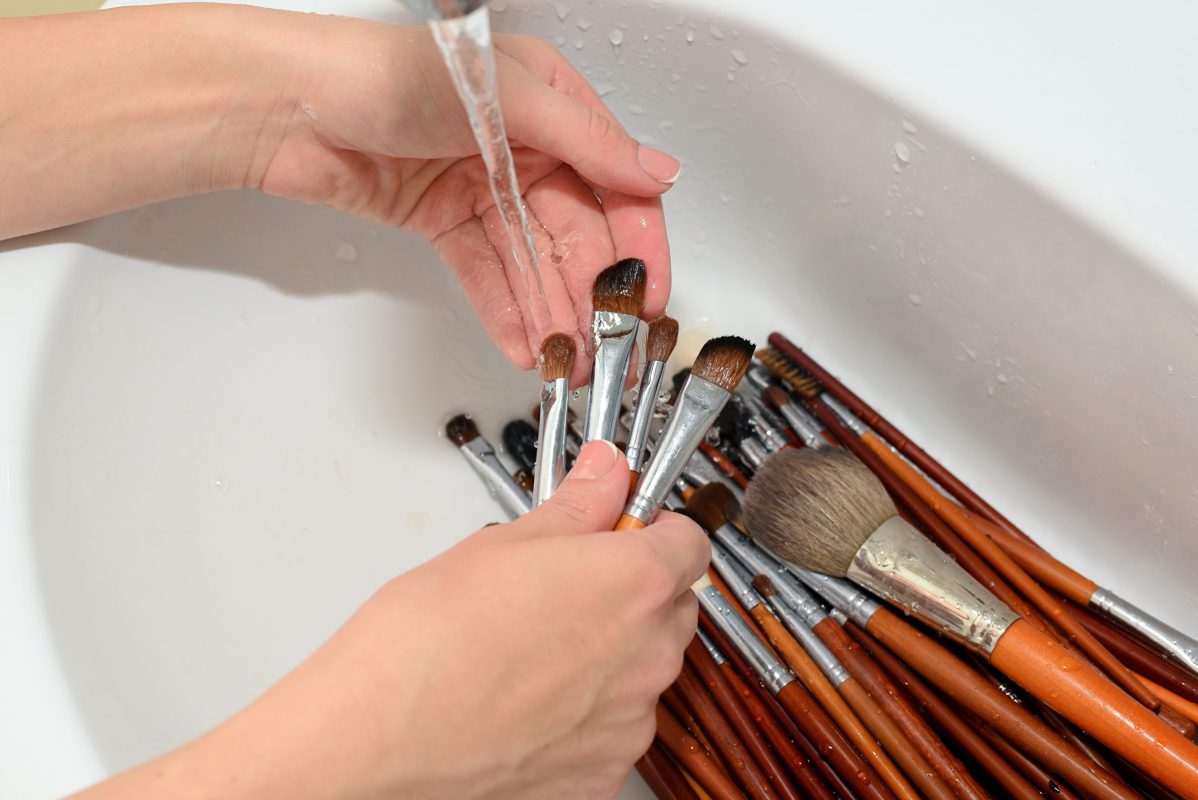 hands of make-up artist washed cosmetic brushes with clean water