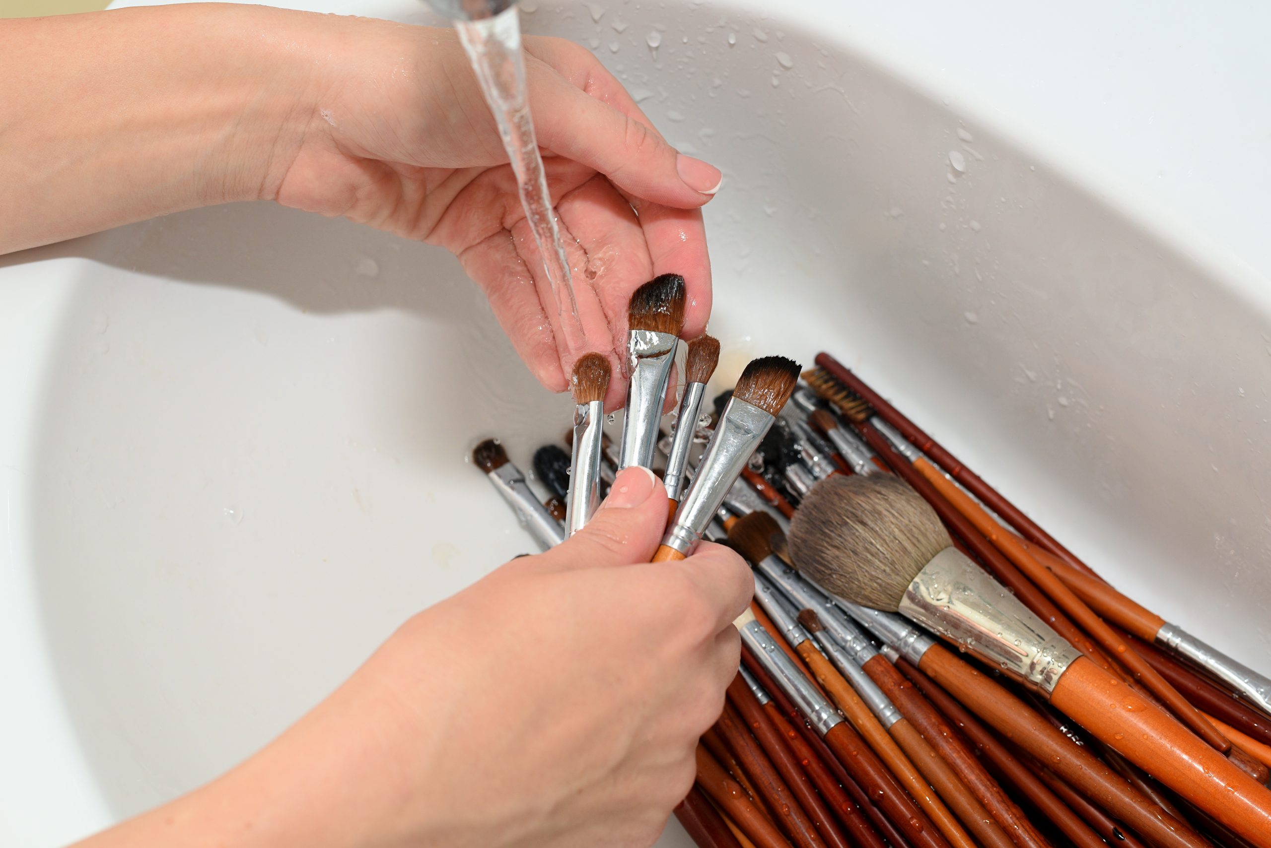 hands of make-up artist washed cosmetic brushes with clean water